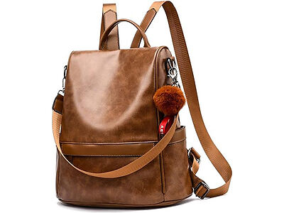 A brown leather backpack with adjustable straps and a small furry pom-pom keychain attached to one side.