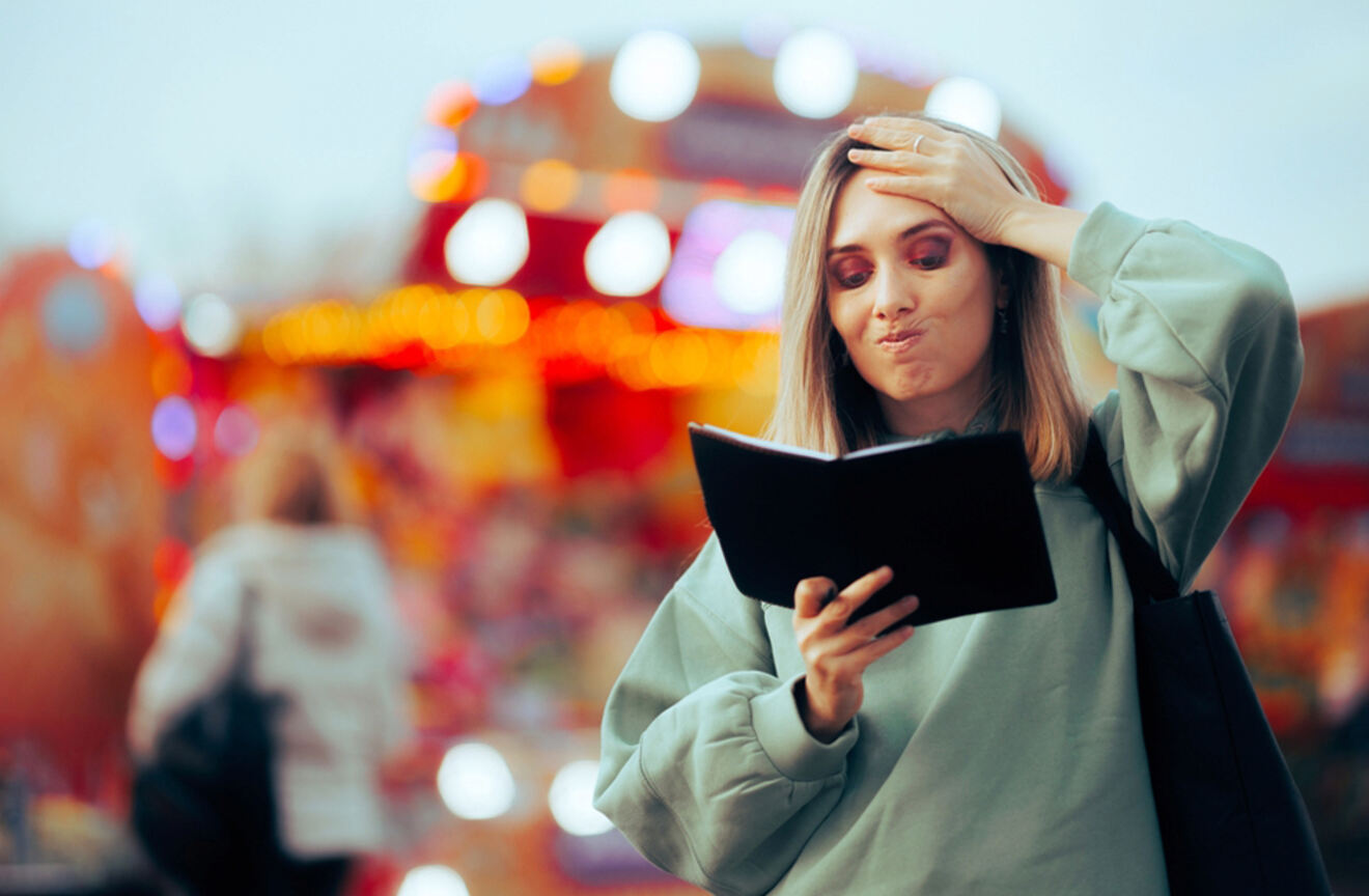 Woman reading a travel guide or notebook with a concerned expression, standing in front of bright, colorful lights