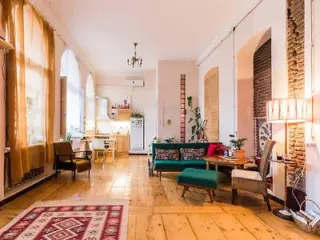 A cozy living area with vintage decor and large arched windows.