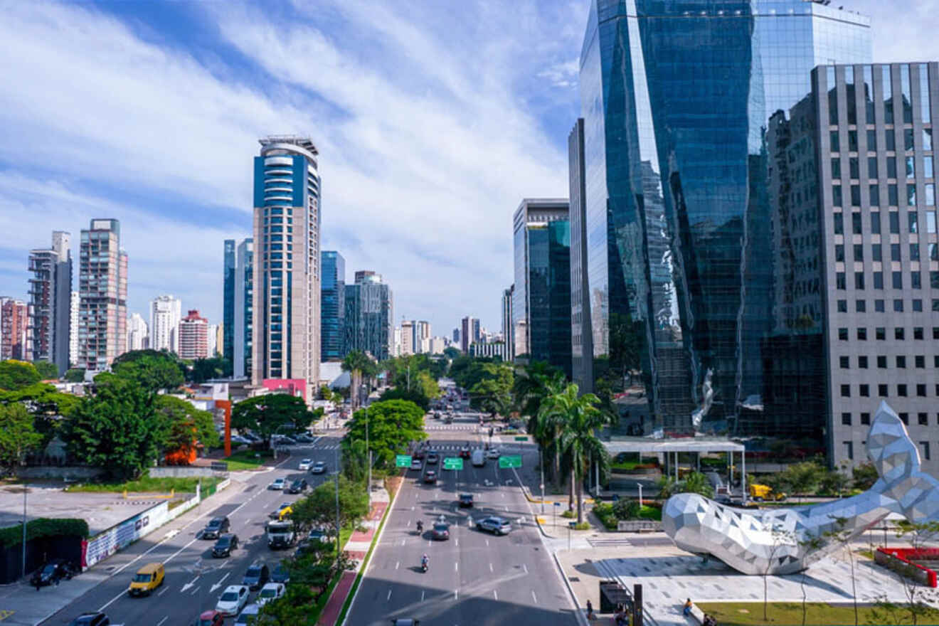 A bustling cityscape with modern skyscrapers, a mix of glass and concrete structures, lining both sides of a busy multi-lane road with vehicles and greenery on the roadside under a partly cloudy sky.
