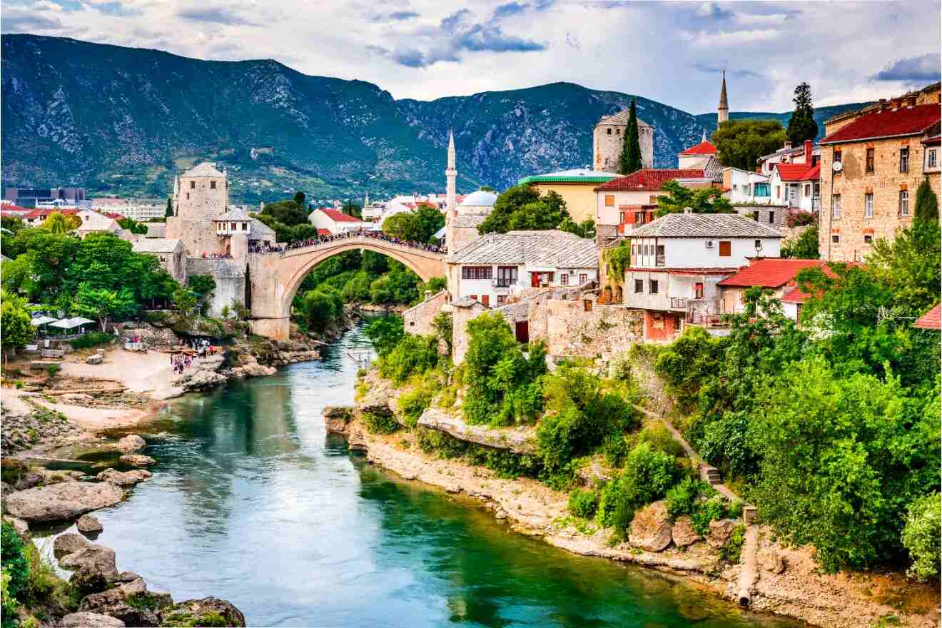 The iconic Stari Most bridge in Mostar, arching over the Neretva River, with a picturesque view of the surrounding town and mountains.