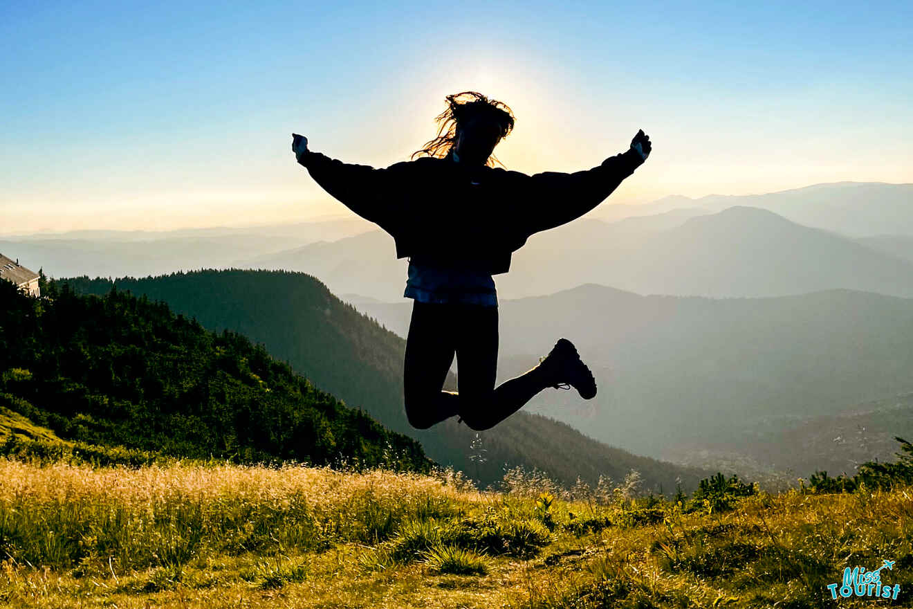Victoria Lupascu, autora de las publicaciones de misstourist, salta en el aire con montañas y un atardecer de fondo. Su silueta se recorta contra el paisaje.