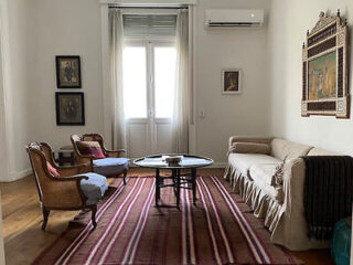Cozy living room with vintage furniture, a striped rug, and framed artwork.