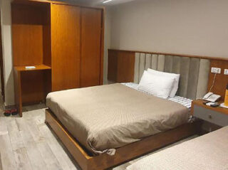 Minimalist bedroom with a double bed, wooden wardrobe, and bedside table.
