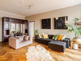 A bright and spacious living room featuring a mix of modern and classic decor with cozy seating and vibrant cushions.