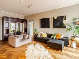 A bright and spacious living room featuring a mix of modern and classic decor with cozy seating and vibrant cushions.
