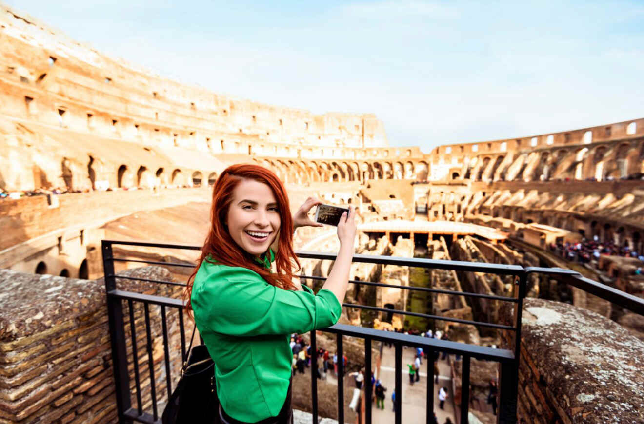 Woman happily taking a selfie in front of the Colosseum in Rome, Italy, indicating enjoyment and capturing memorable travel moments