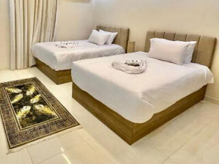 Bedroom with two double beds, white linens, and a decorative rug.
