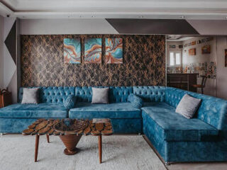 Stylish living room with a large blue sectional sofa and decorative wallpaper.