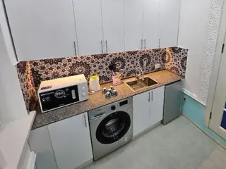 A compact yet functional kitchen featuring modern appliances and colorful patterned tiles.
