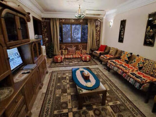 Traditional living room with patterned couches, a large rug, and wooden furniture.