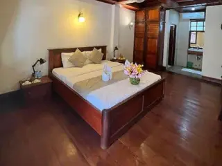 A warmly lit bedroom with a wooden bedframe, soft white linens, and a cozy atmosphere.