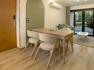 Modern dining area with a wooden table and four chairs, leading to a bright living room.