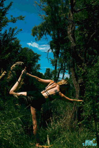 The writer of the post doing a dancer pose in a forest, balancing on one leg while holding the other leg behind.