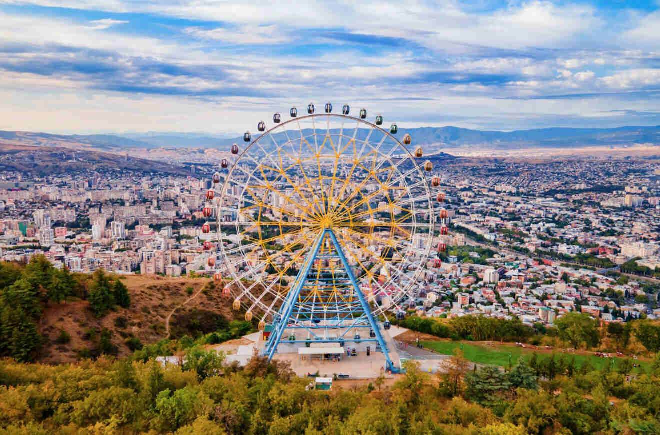 Large Ferris wheel overlooking a cityscape with a panoramic view of the city and surrounding landscape.