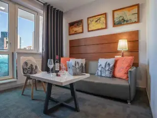 A cozy living area with a modern gray sofa, colorful pillows, and a small table set for two with wine glasses.