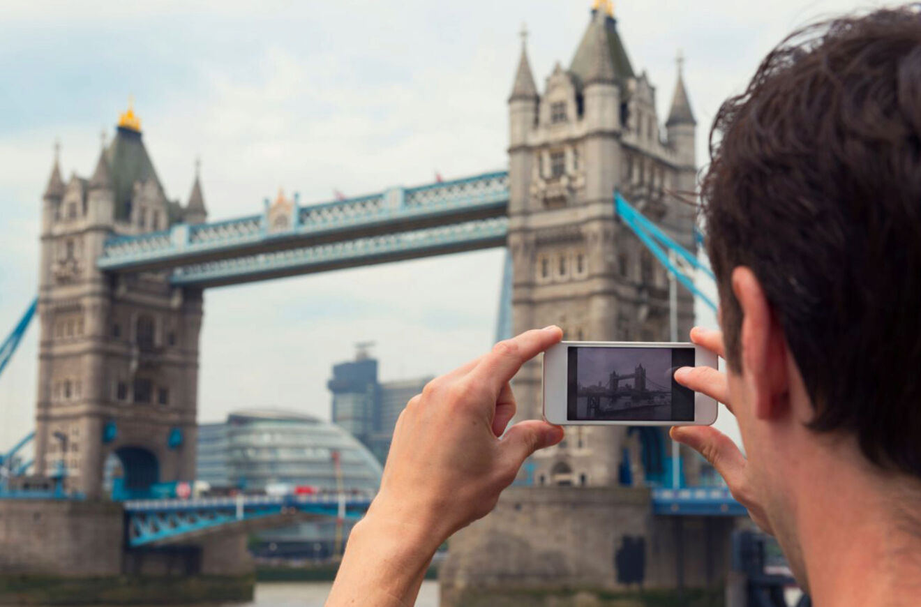 Person taking a photo of Tower Bridge in London with a smartphone.