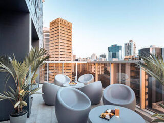 A stylish rooftop terrace with round chairs and a stunning view of the city skyline.