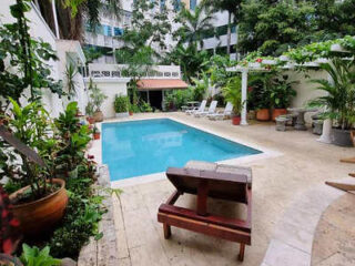 A serene outdoor pool surrounded by lush tropical plants and comfortable lounge chairs.