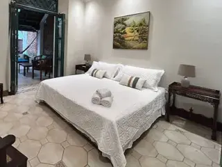 A spacious bedroom with a large white bed, traditional wooden furniture, and an inviting ambiance.