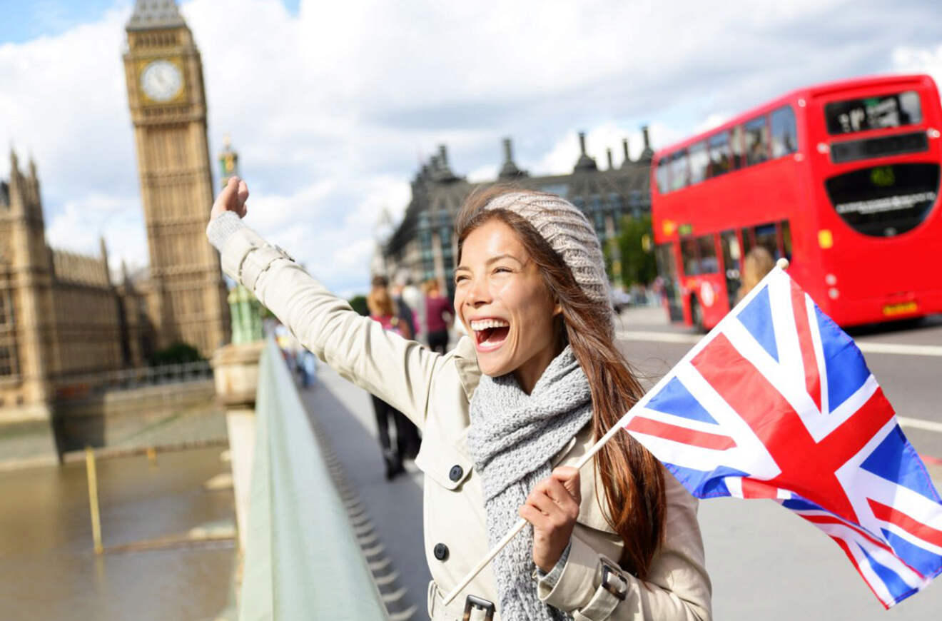 Woman enthusiastically waving a British flag with Big Ben and a red double-decker bus in the background in London, England