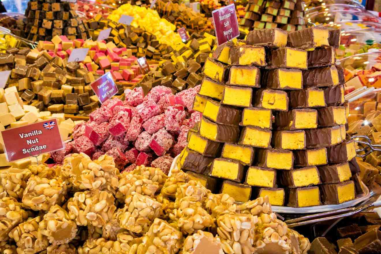 A variety of colorful fudge blocks stacked on display at a market.