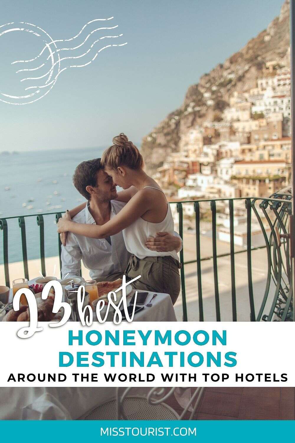 A couple sits at a table on a balcony with a scenic view of hillside buildings at a coastal location. Text overlay reads "13 Best Honeymoon Destinations Around the World with Top Hotels, misstourist.com.