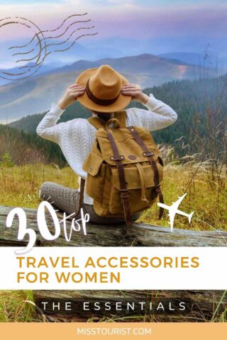 A person wearing a hat and backpack sits on a log overlooking a mountain landscape. Text on the image reads: "30 Top Travel Accessories for Women: The Essentials - misstourist.com".