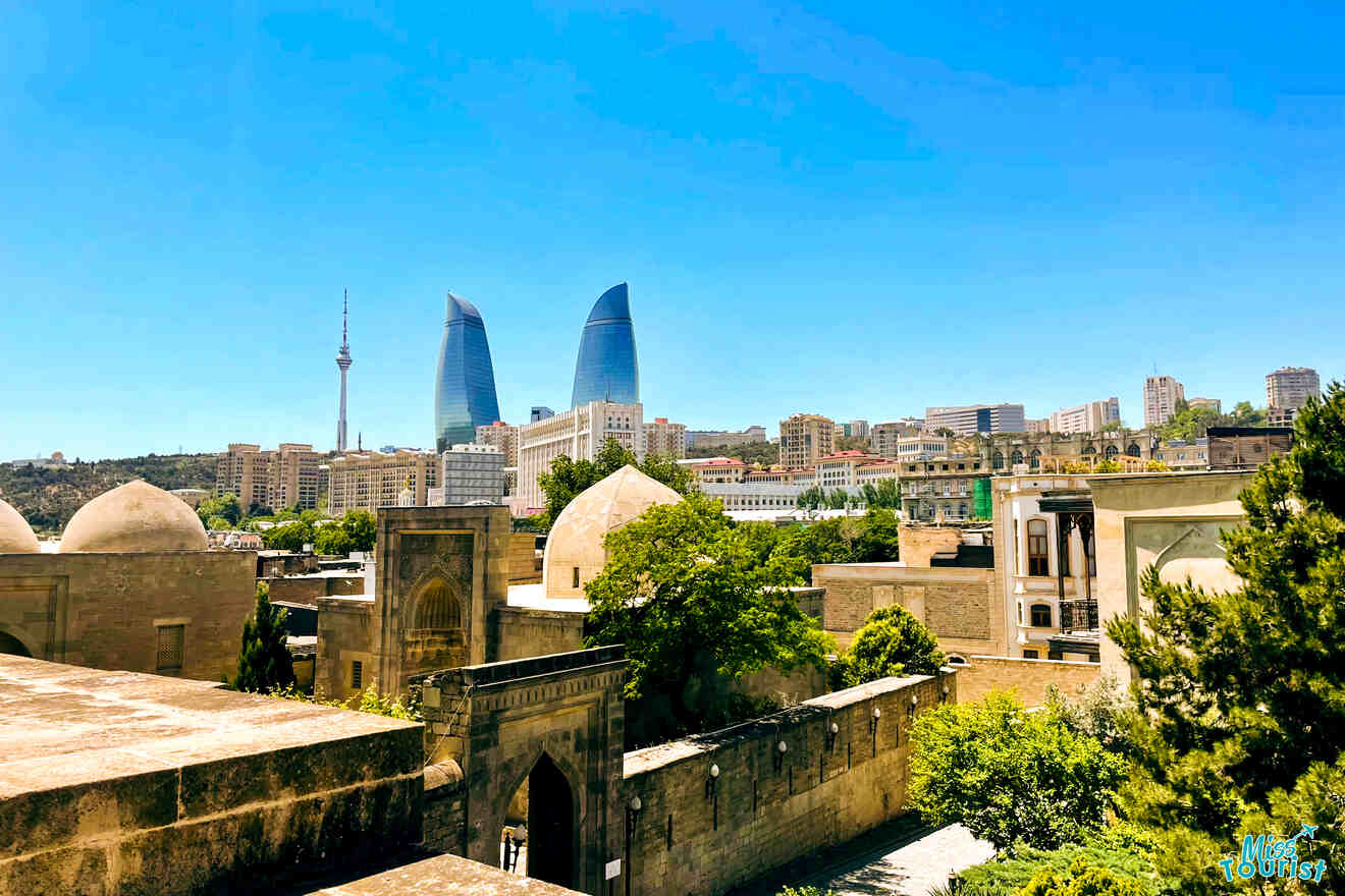 A cityscape view of Baku, showcasing modern skyscrapers and historical architecture under a clear blue sky.