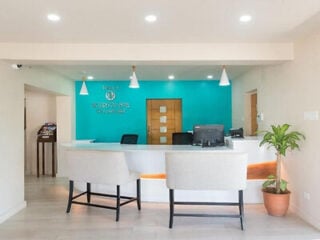Reception desk at Rostrevor Hotel in Barbados, with a curved white counter against a turquoise feature wall, pendant lights and armchairs in the lobby.