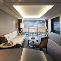 Luxurious hotel suite with a large window offering a stunning sunset view over the water.