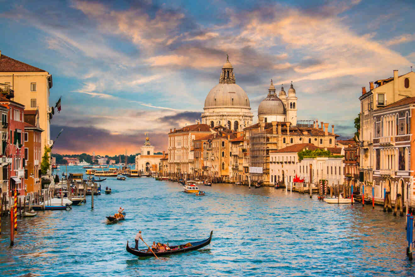 A gondola navigates the Grand Canal in Venice, Italy, with historic buildings and the Santa Maria della Salute church under a vibrant sunset sky.