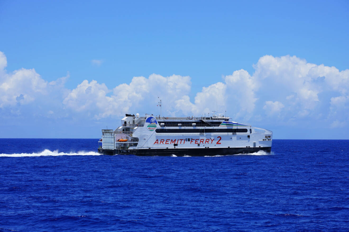 The Aremiti Ferry 2 speeding through the ocean with a backdrop of blue sky and fluffy clouds.