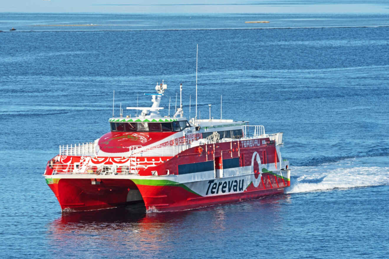 The red Terevau ferry navigating the calm blue waters, showcasing its colorful design.