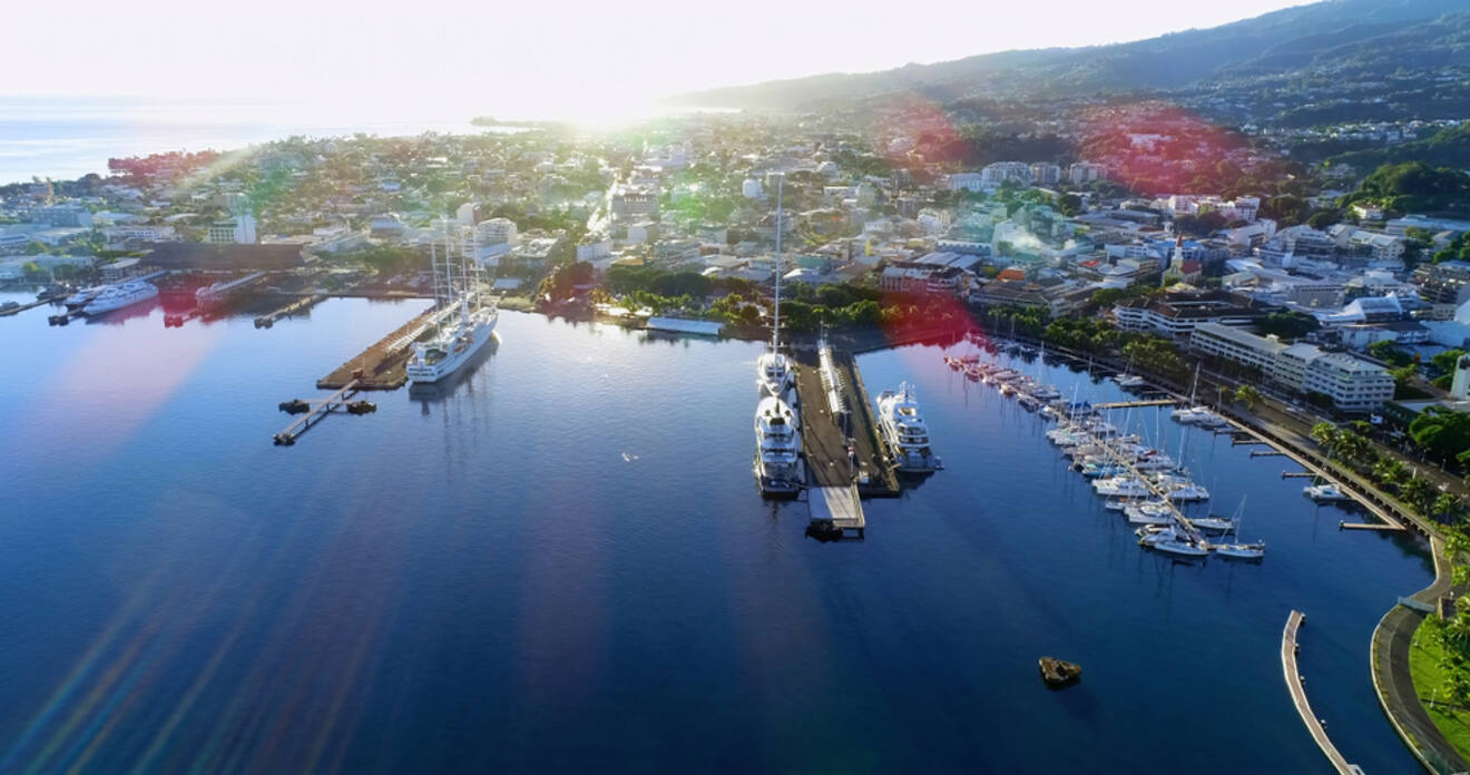 A scenic aerial view of a harbor with multiple ferries and boats docked, surrounded by a coastal city.