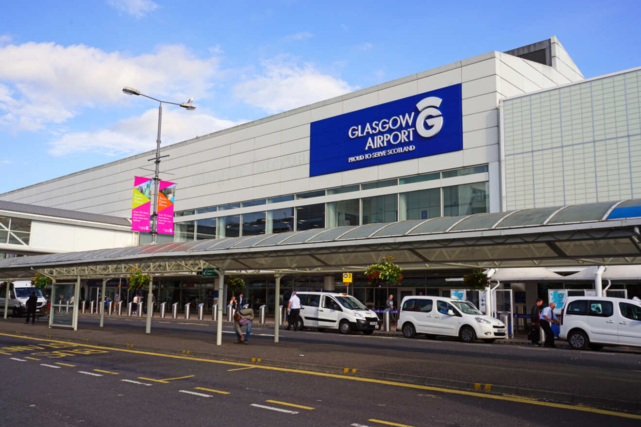 The front view of Glasgow Airport, with a prominent sign reading "Glasgow Airport: Proud to Serve Scotland," and people and vehicles outside the main entrance.