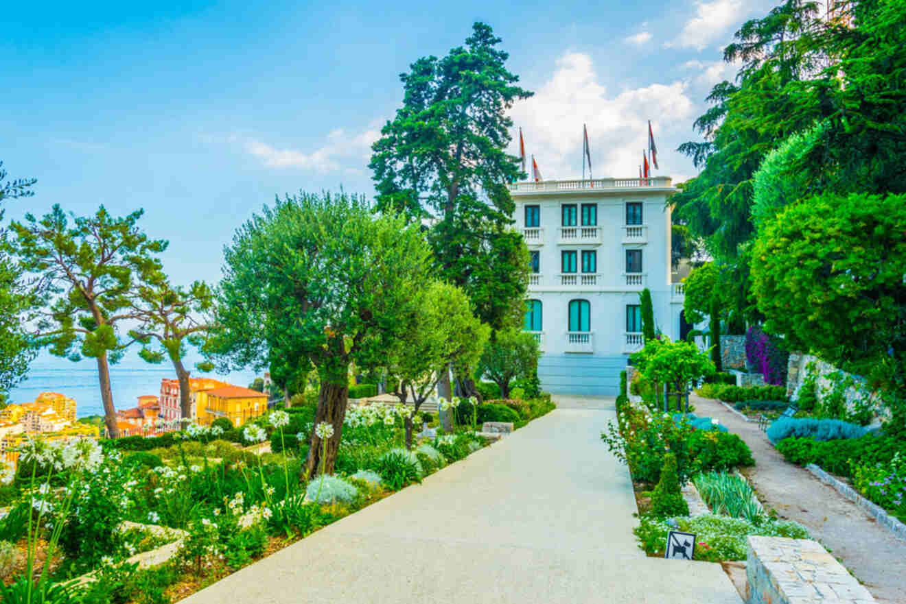 A pristine white building of the Nouveau Musée National de Monaco surrounded by lush gardens and trees.