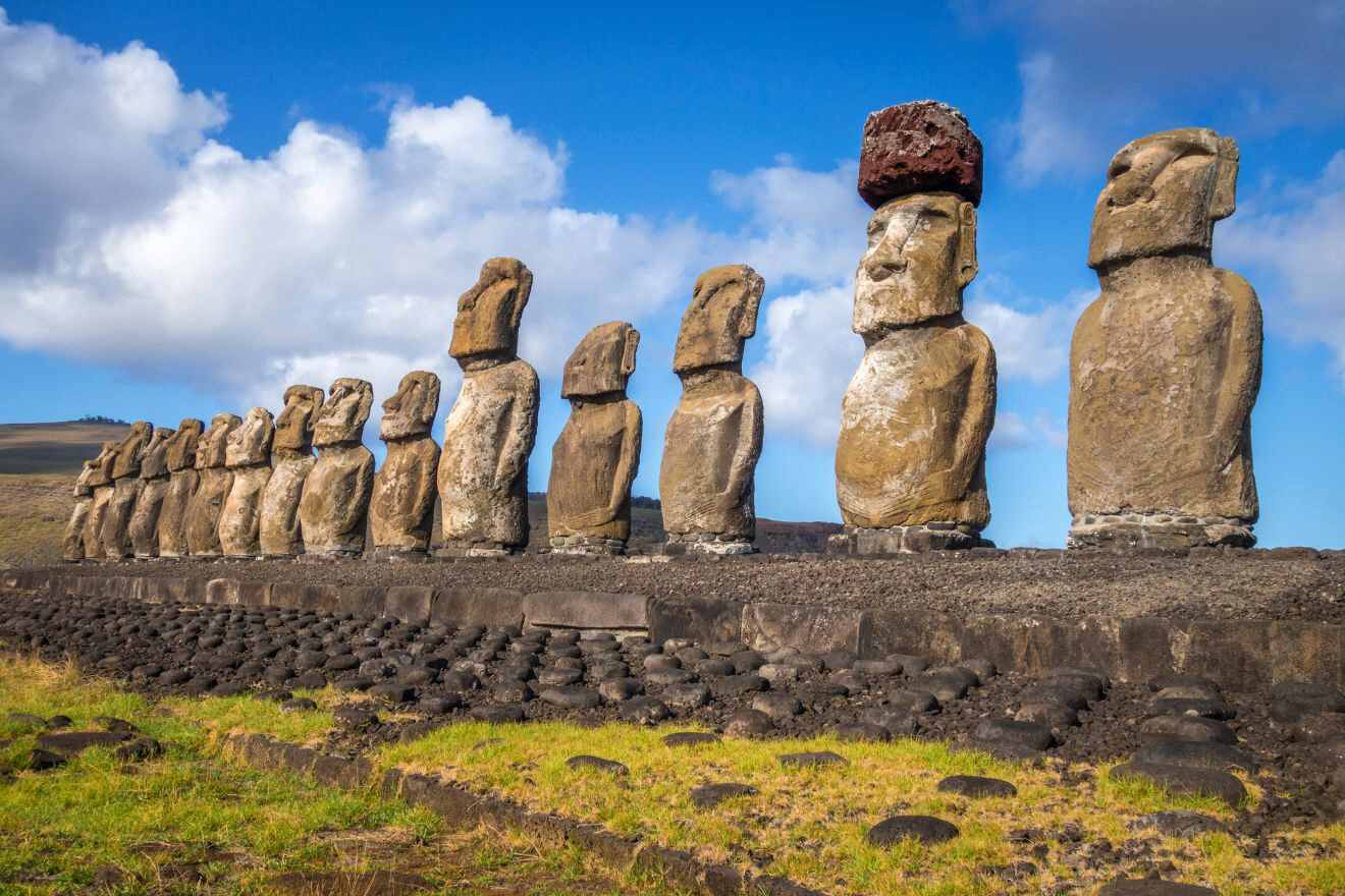 Row of ancient Moai statues standing on a platform on Easter Island under a partly cloudy sky.