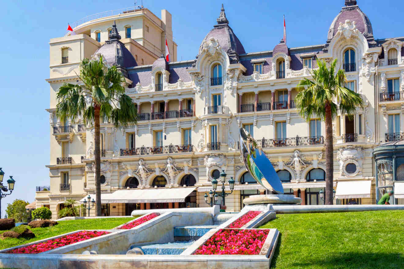 The elegant exterior of Le Louis XV - Alain Ducasse restaurant at the Hôtel de Paris in Monaco, featuring manicured gardens and a sleek, reflective sculpture.