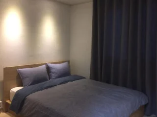 Simple bedroom with a double bed and dark curtains.
