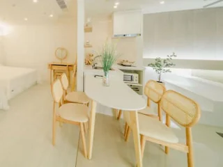 Bright, modern studio apartment with light-colored furniture and an open kitchen.