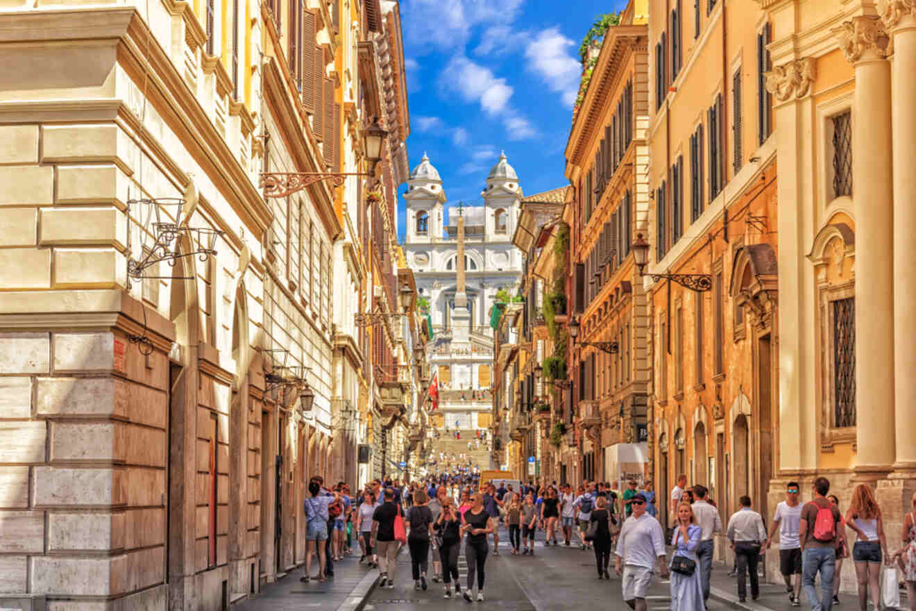 A busy street in Rome leading to the Spanish Steps, filled with pedestrians and historic buildings.
