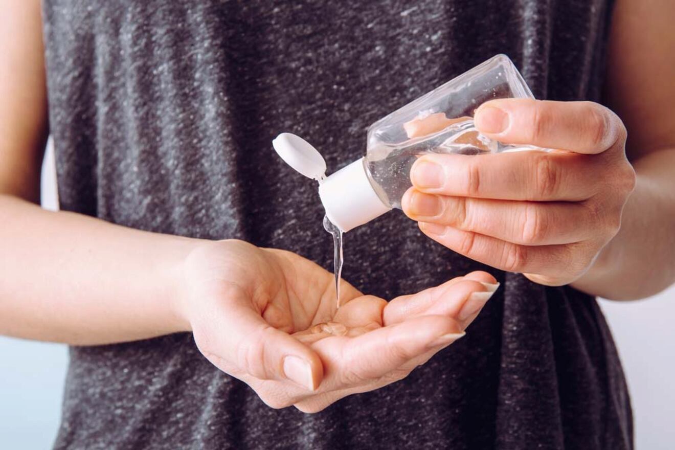 A person pours hand sanitizer from a small bottle into their hand.