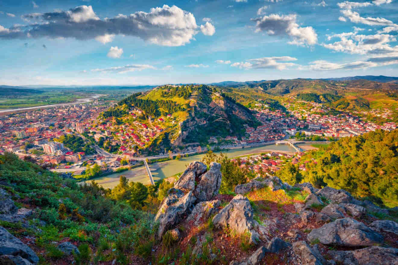 A panoramic view of a vibrant city nestled in a lush, mountainous landscape, with a river running through it.