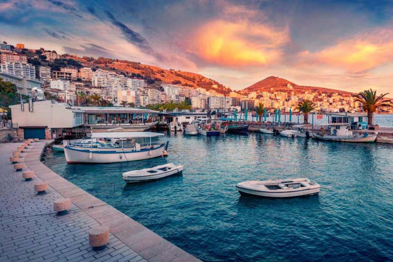 Boats docked at a marina in front of a coastal city, with a stunning sunset casting colorful hues over the water and hills.