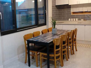Dining area with a large table and chairs next to a kitchen.