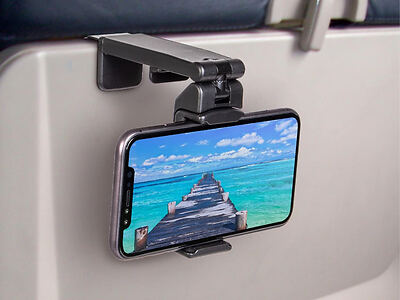 Smartphone mounted on an airplane tray table, displaying an image of a boardwalk leading to the ocean under a clear blue sky.