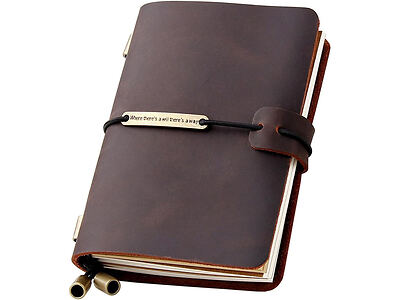 A brown leather notebook with a closure strap and a pen holder. The strap features a metal tag with engraved text. The notebook contains unlined pages.