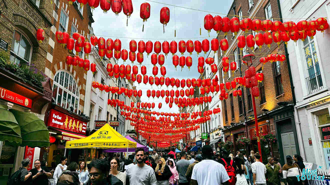 Crowded street in Soho, London, adorned with numerous red lanterns during the day.