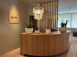 A spa reception area featuring a wooden counter, decorative lighting, and potted plants.